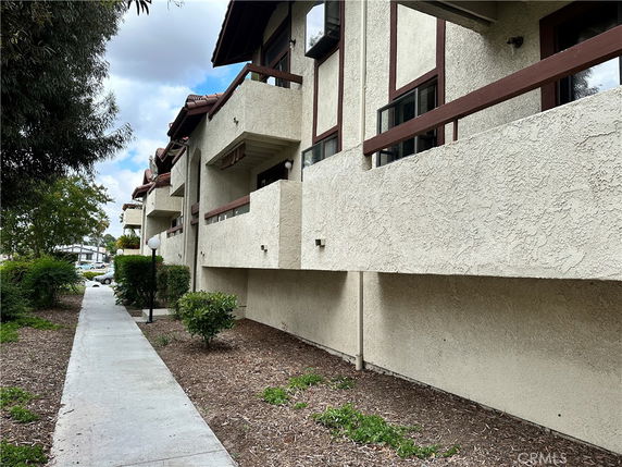 Side view of a multi-story building with balconies and textured walls.
