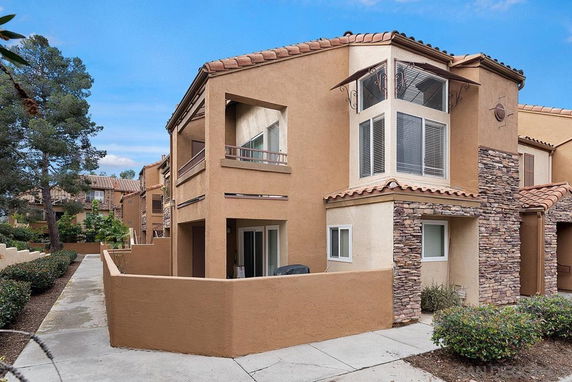 Front view of a two-story house with a balcony and stone accents.