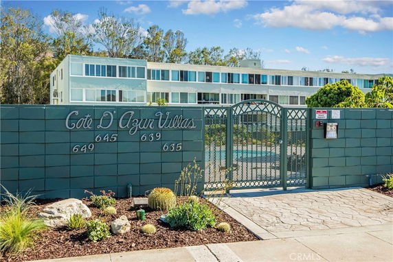 Front view of a multi-story apartment building with a gated entrance.