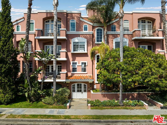 Front view of a multi-story building with white framed windows and a terracotta tile roof.