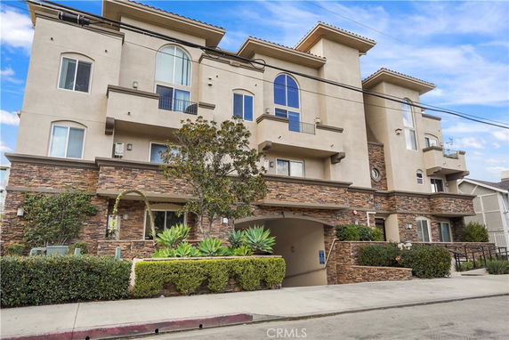 Front view of a multi-story residential building with stone accents and balconies.