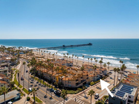 Aerial view of a coastal area with buildings and a pier extending into the ocean.