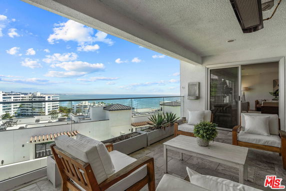 Balcony view of a coastal area with modern buildings and ocean in the background.
