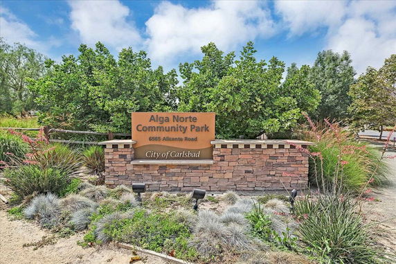 Sign for Alga Norte Community Park surrounded by plants and trees.