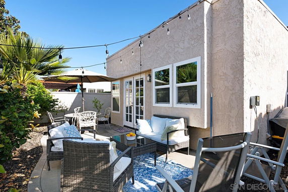 Front view of a single-story house with a small patio area and outdoor seating.