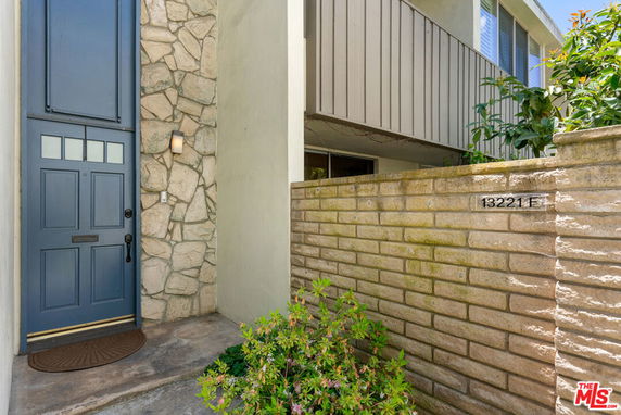Front view of a house with a blue door and stone wall.