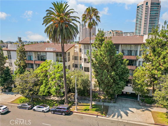 Front view of a multi-story apartment building with tall palm trees in front.