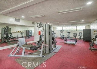 Indoor gym with exercise equipment and red carpeted floor.