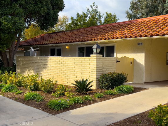Front view of a single-story house with a red tile roof and brick exterior wall.