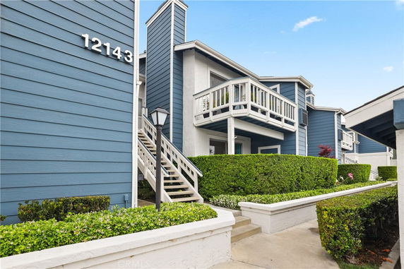 Front view of a multi-story building with blue siding and a stairway entrance.