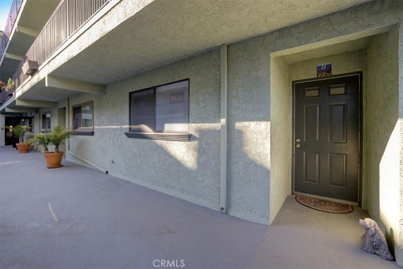Exterior view of a building hallway with multiple doors and windows.