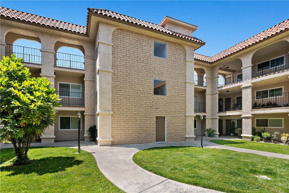 Front view of a multi-story apartment building with balconies and a central courtyard.