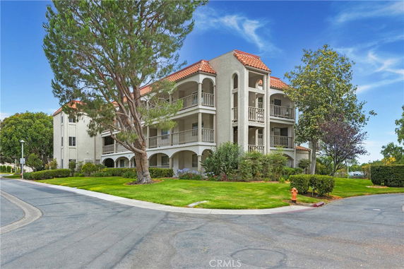 Front view of a three-story building with balconies and red-tiled roof.