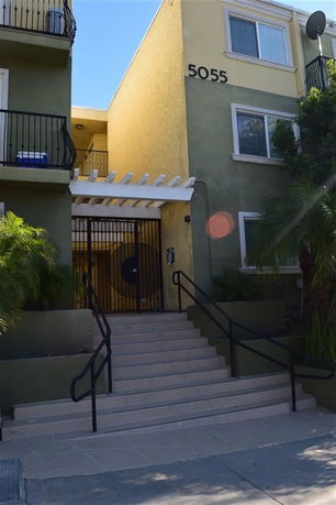 Front view of a multi-story residential building with a gated entrance and staircase.