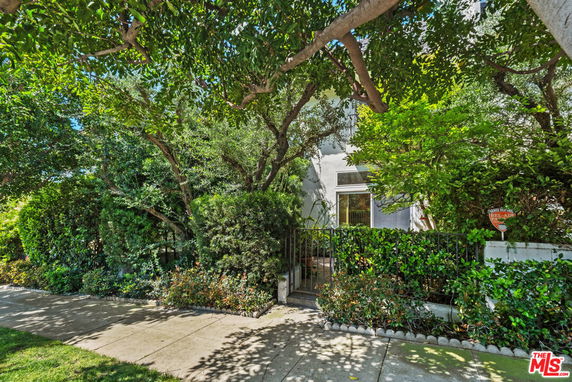 Front view of a house partially obscured by trees and greenery.