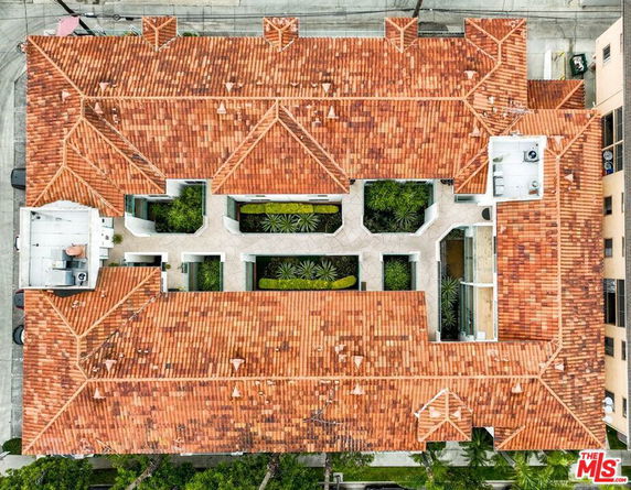 Aerial view of a building with a red-tiled roof and open courtyards.