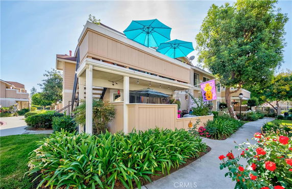 Front view of a two-story house with balconies and blue umbrellas.