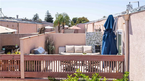 Rooftop terrace with seating, umbrella, and plants.