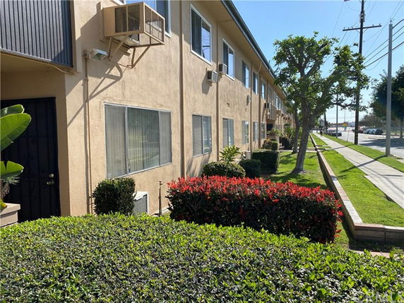 Front view of a multi-story beige building with air conditioning units and windows.
