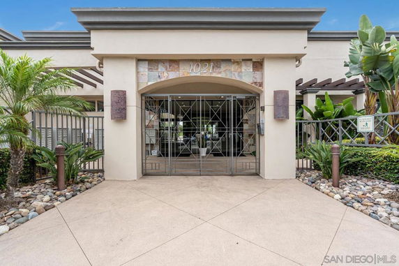 Front view of a modern building entrance with decorative stonework and metal gates.