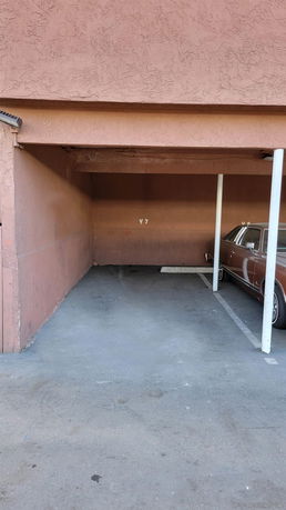 A covered outdoor parking space with one parked car and empty space marked 'V7'.