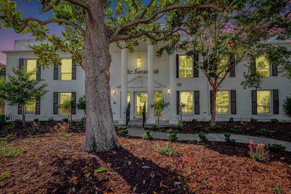 Front view of a two-story house with classical columns and multiple windows.