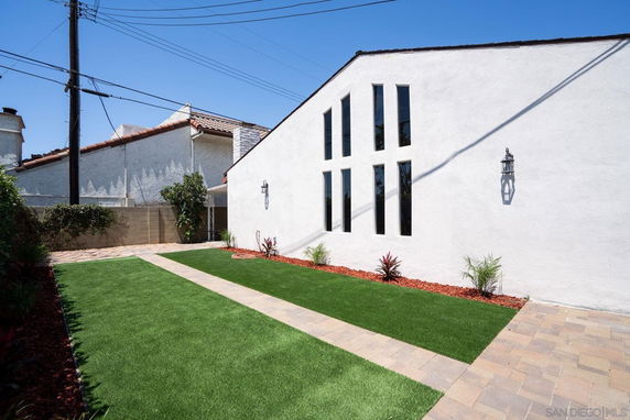 Front view of a house with tall narrow windows and a landscaped garden.