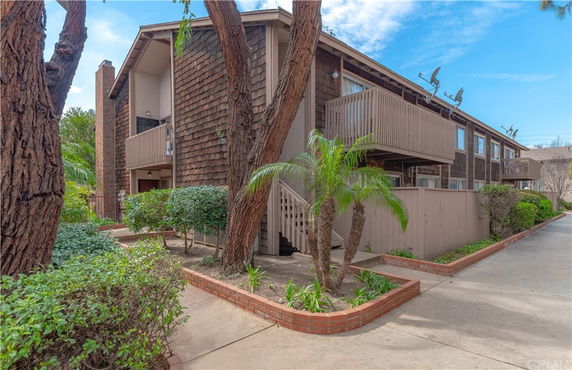 Front view of a multi-story residential building with balconies and wooden exterior.