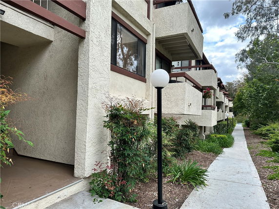 Front view of a multi-story building with balconies and outdoor walkway.