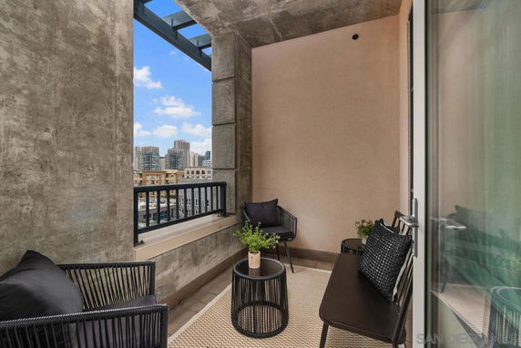 A balcony area with seating and a view of city buildings.
