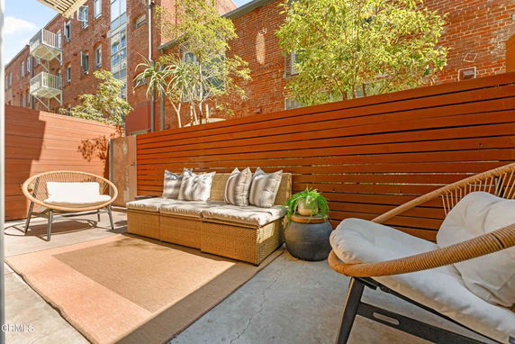 Outdoor seating area with wicker furniture and a wooden privacy fence.