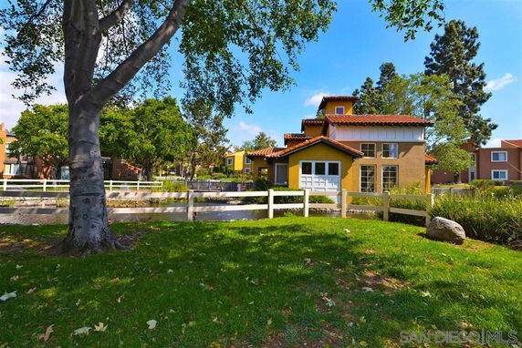 Front view of a house with multiple gabled roofs and a small fenced yard.