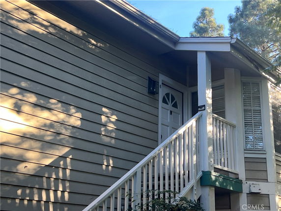 Front view of a house with a staircase and wooden siding.