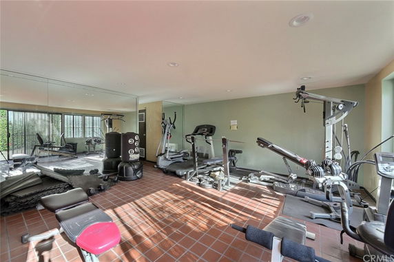 Indoor gym area with various exercise equipment and large mirrors on the walls.