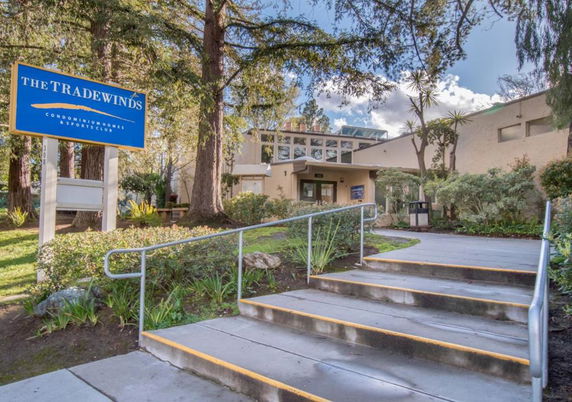Front view of a building with a sign reading 'The Tradewinds' and a pathway leading to the entrance.