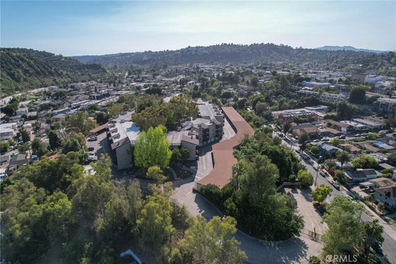 Aerial view of apartment complex with surrounding neighborhoods and hills.