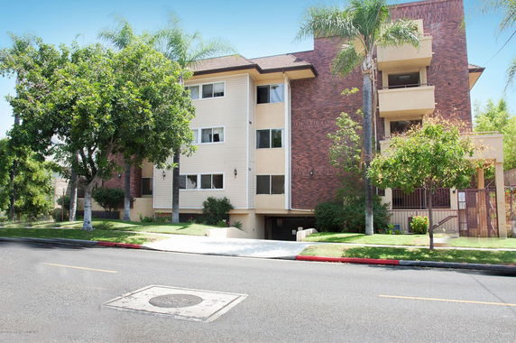 Front view of a multi-story residential building with a brick facade and balconies.