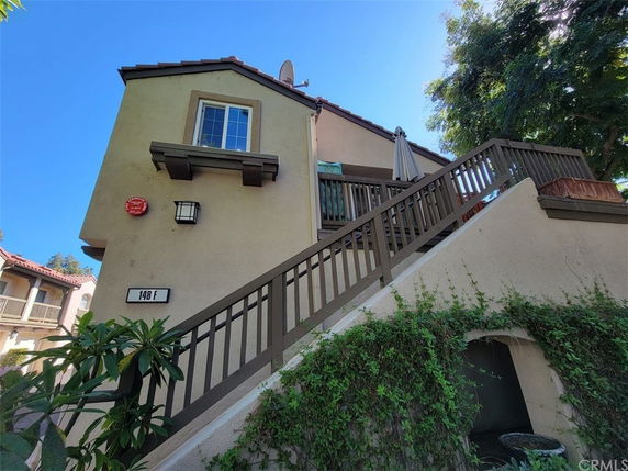 Front view of a two-story house with an external staircase and a balcony.