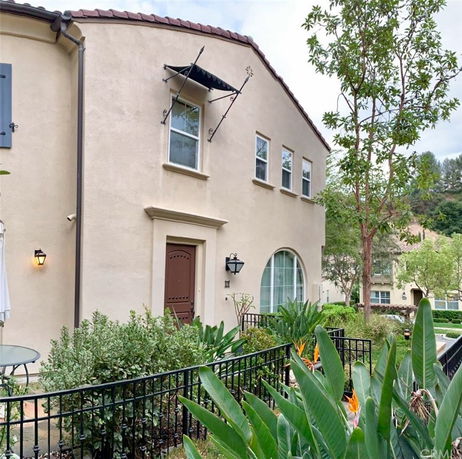 Front view of a two-story house with arched and rectangular windows, and a red door.