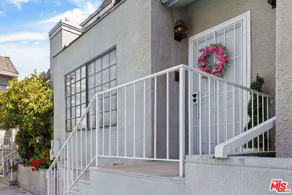 Front view of a house with steps leading to a door adorned with a floral wreath.