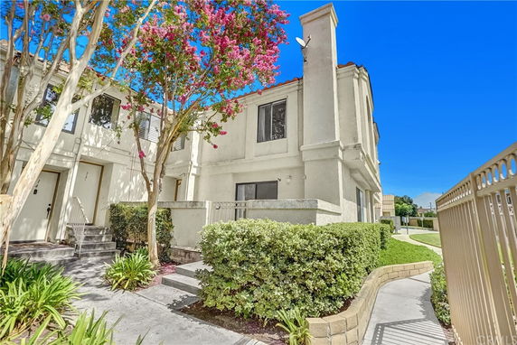 Front view of a multi-story townhouse with a small front yard and entrance path.