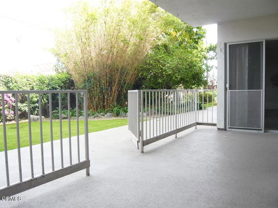 Patio view with metal railings and sliding glass door, overlooking a garden area.