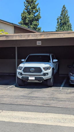 Covered outdoor parking area with a parked white vehicle.