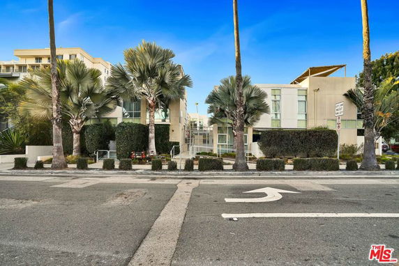 Front view of a modern two-story building with palm trees in front.
