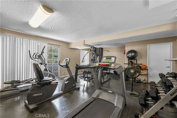 Indoor gym area with exercise equipment including treadmills, exercise bikes, and dumbbells.
