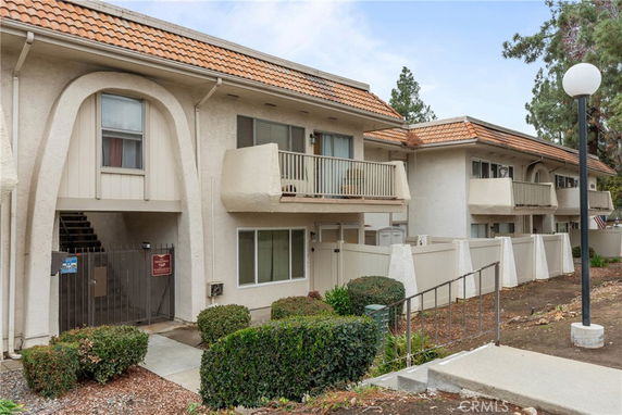 Front view of a two-story apartment building with balconies and a gated entrance.