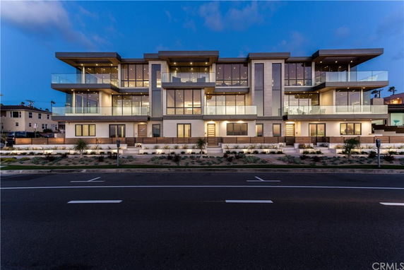 Front view of a modern multi-story building with balconies and large windows.