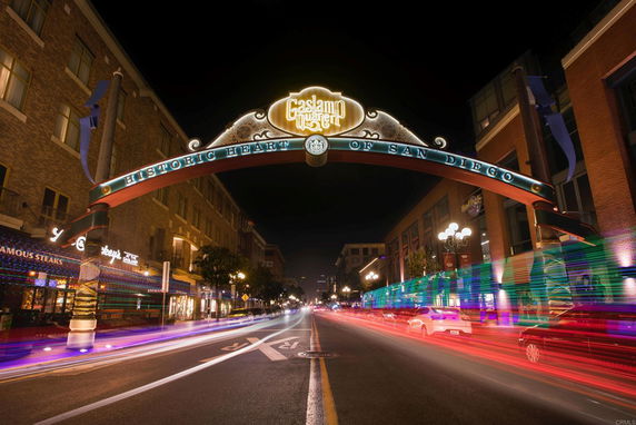 Night view of a street with an illuminated archway sign reading 'Gaslamp Quarter' in a city setting.