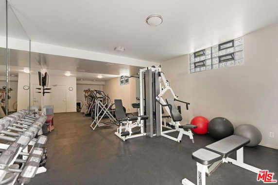 A gym area with exercise equipment, weights, and mirrored walls.