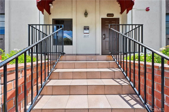 Front view of a building entrance with steps and railing.